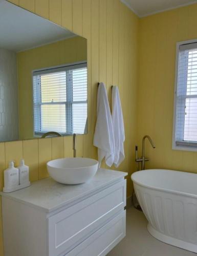 a bathroom with a sink and a tub and a mirror at Daffodil on Owen in Huskisson
