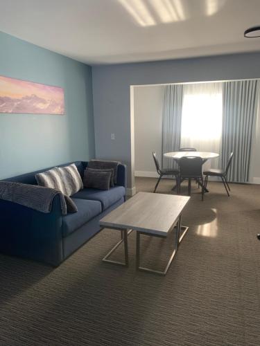 a living room with a blue couch and a table at Anchor Inn and Suites in Campbell River