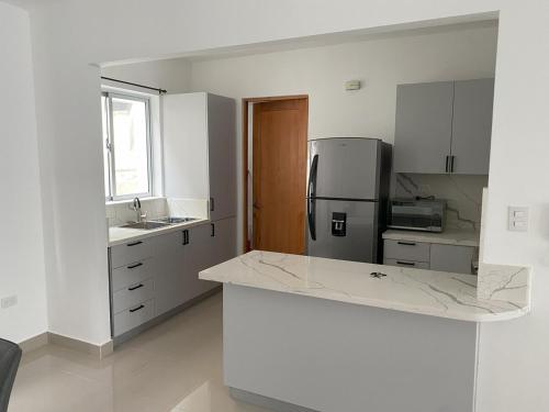 a white kitchen with a refrigerator and a sink at Cozy Tropical Getaway in Los Altos de Jalisco
