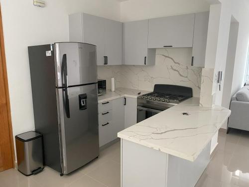 a kitchen with a stainless steel refrigerator and white cabinets at Cozy Tropical Getaway in Los Altos de Jalisco