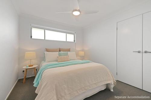 a white bedroom with a bed and a window at Beachstay Hideaway Vincentia by Book Jervis Bay in Vincentia