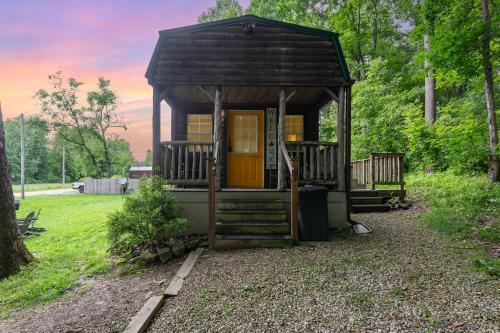 a small cabin in the woods with a yellow door at Acorn Cottage at Hocking Vacations in Logan