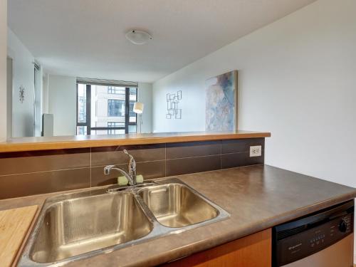 une cuisine avec un évier en acier inoxydable et un comptoir dans l'établissement Astoria Escape - Bright condo with work desk by Victoria Prime!, à Victoria