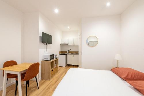 une chambre blanche avec un lit et une table dans l'établissement Studio lumineux et confortable Proche Douai Centre, à Douai