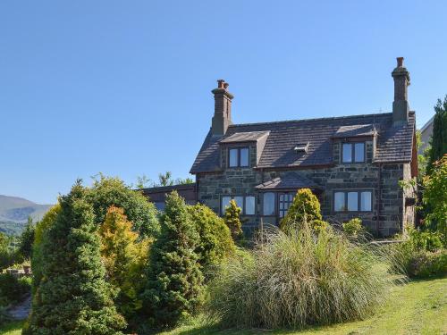 an old stone house with bushes in front of it at Y Bwthyn in Llandegai