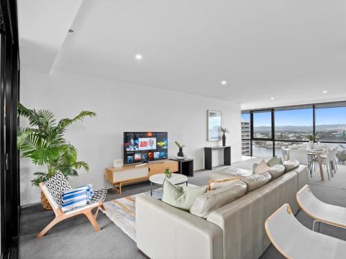 Una sala de estar con un sofá y un televisor. en 2BR Unit Heart of Surfers Paradise - Spa, Pool, en Gold Coast