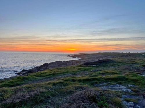 a sunset over the ocean with a rocky beach at Pet-Friendly Getaway in Quéven