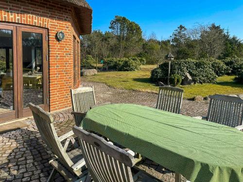 a table and chairs with a green tablecloth on a patio at Octagonal Thatched Forest House Near Herning in Videbæk