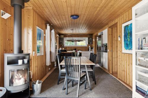 une salle à manger avec une table, des chaises et un poêle dans l'établissement Enjoy Outdoor Life With Orangery And Kitchen, à Græsted
