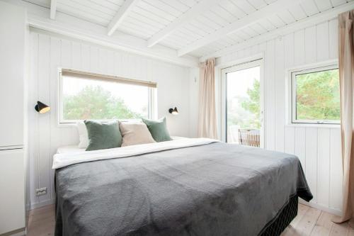 Un dormitorio blanco con una cama grande y dos ventanas. en Seaside Cabin With Ocean View And Sunny Terrace, en Søgne