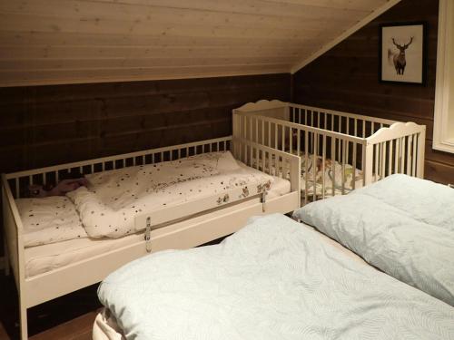 two white cribs in a room with two beds at Mountain Cabin With Views Over Nesfjellet in Nesbyen