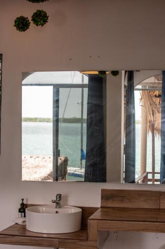 a bathroom mirror with a sink and a view of a beach at Seven Blue House Village & Lodge in Bacalar