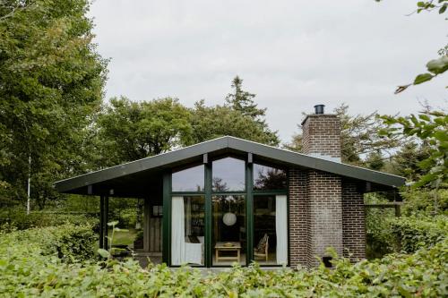a small brick house with a black roof at Warm 70S Vibe Near Limfjord in Løgstør