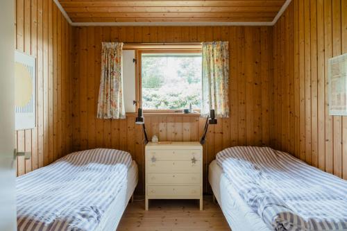 two beds in a wooden room with a window at Warm 70S Vibe Near Limfjord in Løgstør