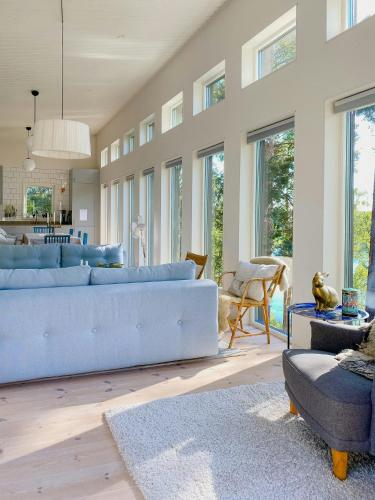 a living room with a blue couch and a table at Modern Glass House With A View Over Lake Lejondal in Bro
