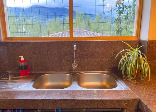 a sink in a kitchen with a window above it at Watzara Wasi Dpt Familiar cerca de Cuicocha in Cotacachi
