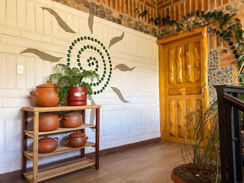 a shelf with plants and a wreath on a wall at Watzara Wasi Dpt Familiar cerca de Cuicocha in Cotacachi