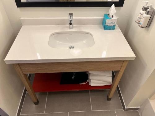 a sink in a bathroom with a red shelf under it at Tapa Hotel, Inn & Suites in Mahwah