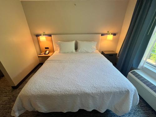 a bedroom with a white bed with two pillows and a window at Tapa Hotel, Inn & Suites in Mahwah