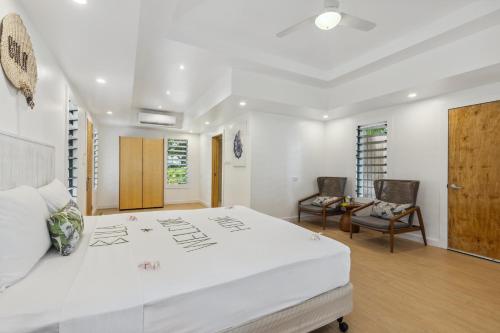 a white bedroom with a large white bed and chairs at Beachcomber Island Resort in Beachcomber Island