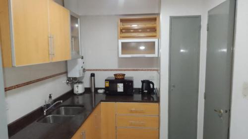 a small kitchen with a sink and a microwave at Dto dos dormitorios cerca del Español, Italiano, HPR, Club Provincial, Predio de la ex Rural in Rosario