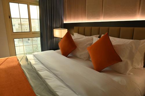 a large white bed with orange pillows and a window at فندق امان أبها - المعالي in Abha