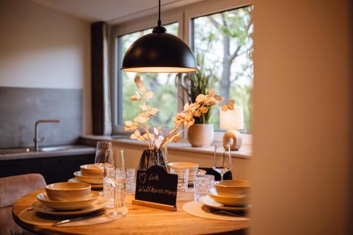 a table with plates and glasses and a lamp at VISAMA, moderne Apartments an der Fulda-Aue in Fulda