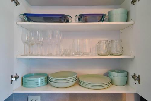 a shelf filled with glasses and plates and bowls at Caribbean Nature Sourrounded Refuge Apartment in Juan Dolio