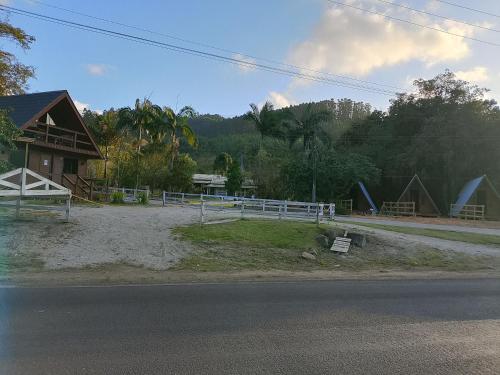 una fattoria con una staccionata bianca e una casa di Pousada Vale das Pedras 03 a Pedras Grandes