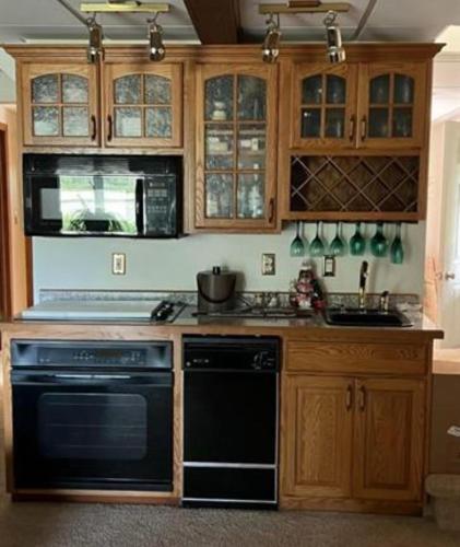 a kitchen with wooden cabinets and a black stove top oven at Sandy Lake Lodge in Toivola