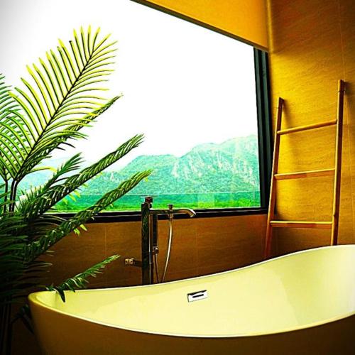 a bath tub in a bathroom with a large window at Viewpoint Khaoyai Hotel in Mu Si