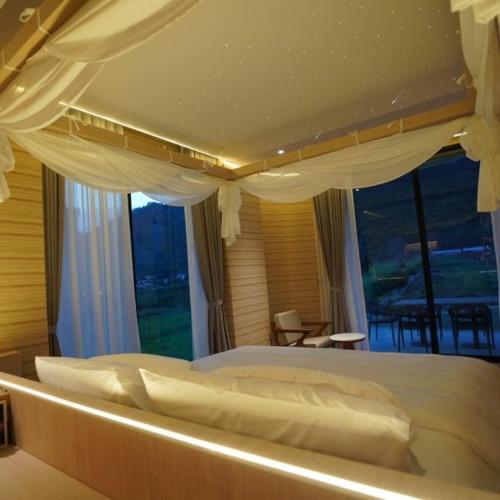 a bedroom with a large bed with white drapes at Viewpoint Khaoyai Hotel in Mu Si