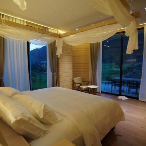 a bedroom with a large bed with a large window at Viewpoint Khaoyai Hotel in Mu Si