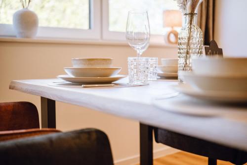 a dining room table with dishes and a wine glass at VISAMA, moderne Apartments an der Fulda-Aue in Fulda