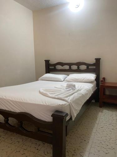 a bedroom with a large bed with white sheets at Hotel Calima Real Tulua in Tuluá