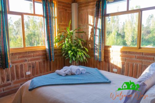 a bedroom with two towels on a bed with windows at Watzara Wasi Dpt Familiar cerca de Cuicocha in Cotacachi