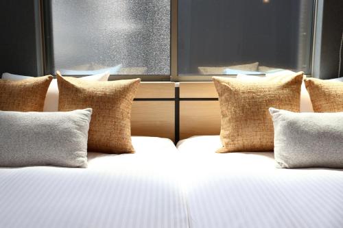 een bed met kussens en een raam in een kamer bij New open 岸里玉出 Maison Le Jaune 玉子心斋桥道顿崛电车直达 in Osaka