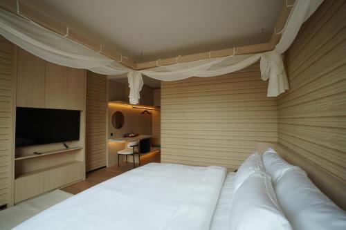 a bedroom with a white bed and a flat screen tv at Viewpoint Khaoyai Hotel in Mu Si