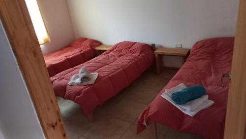 three beds in a room with red sheets and towels at Cabañas Mi Viejo in El Hoyo