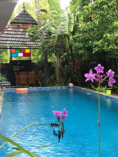 a pool with blue water and purple flowers on it at Mandaram villas in Mararikulam