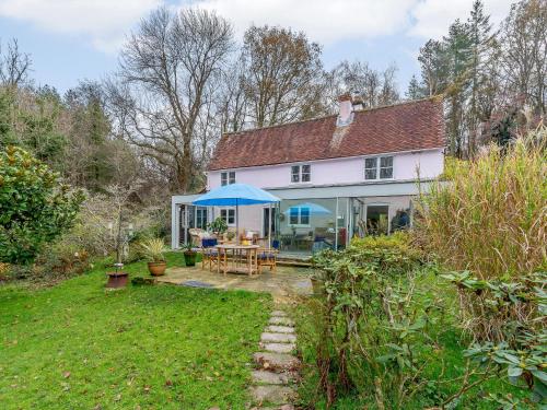 a white house with a table and a blue umbrella at Highlands Farmhouse in Dallington