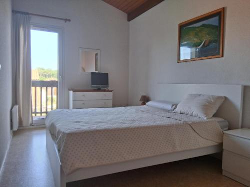 a bedroom with a bed and a television and a window at Villa patio avec piscine, à 400m des commerces et 6km de plage - Animaux admis - FR-1-239-83 in Seignosse