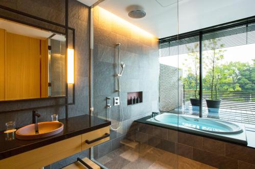 a bathroom with a tub and a sink and a window at Garrya Nijo Castle Kyoto in Kyoto