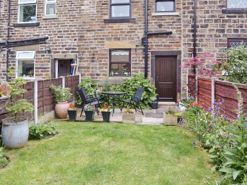 a patio with a table and chairs in a yard at Park View Cottage in Old Glossop
