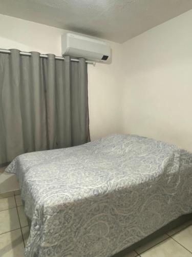 a bedroom with a bed and a window with curtains at Apto Completo com Cozinha Equipada in Valparaíso de Goiás
