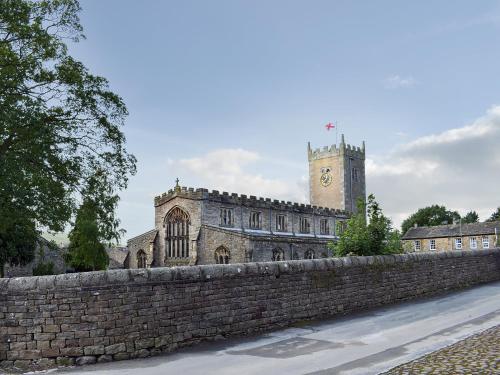 an old building with a clock tower and a stone wall at 3 Winville Mews in Askrigg