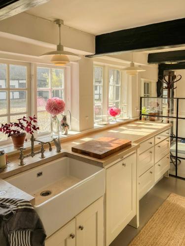 cocina blanca con fregadero y ventanas en Historic Skipper Farm Near Nordby Hills And Beach, en Nordby
