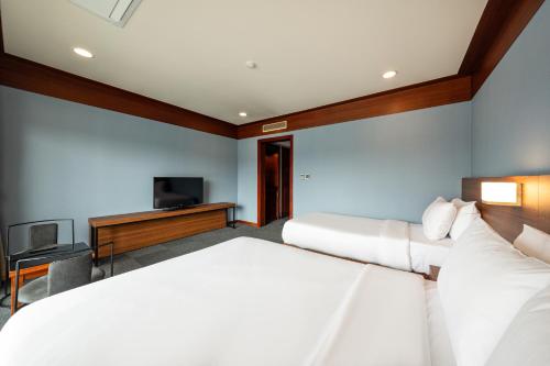 a hotel room with two beds and a television at The Hill House Yangpyeong in Yangpyeong