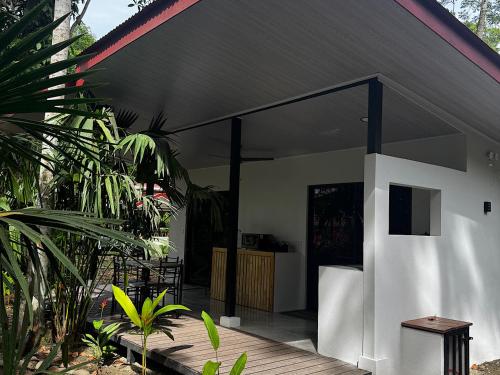 a white house with a black roof with a wooden deck at El Rincon de la Suiza in Cahuita