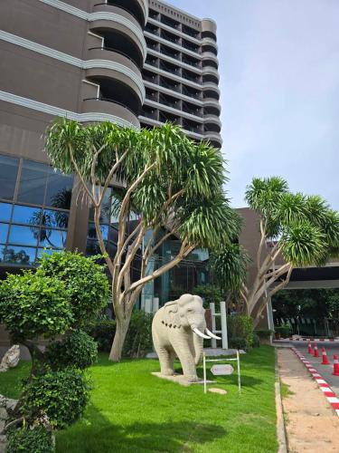 a statue of an elephant sitting on the grass in front of a building at First Pacific Cirrus in Pattaya Central